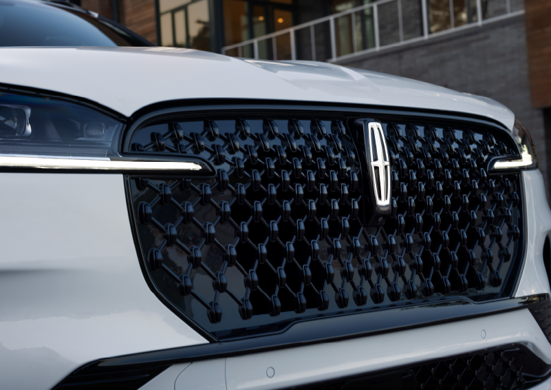 The black grille of a white 2025 Lincoln Aviator® SUV is shown with its fog lights on. | Oliver Lincoln in Plymouth IN