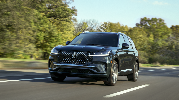 A 2025 Lincoln Black Label Aviator® SUV is being driven down a road lined with trees. | Oliver Lincoln in Plymouth IN