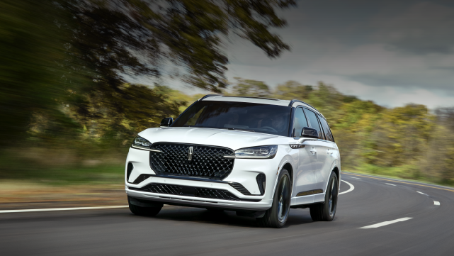 A white 2025 Lincoln Aviator® SUV is being driven down a road lined with trees. | Oliver Lincoln in Plymouth IN