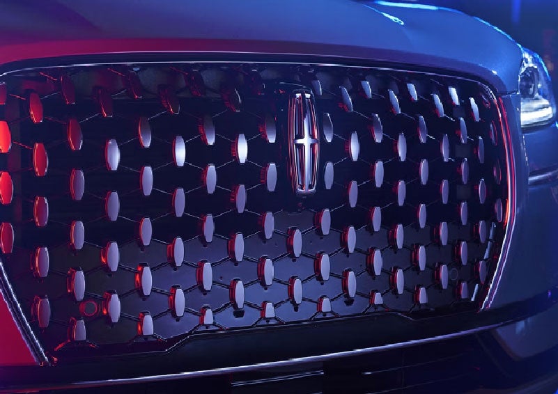 The grille of a 2025 Lincoln Corsair® SUV reflects neon light at night. | Oliver Lincoln in Plymouth IN