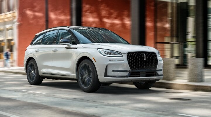 A white 2025 Lincoln Corsair® SUV with the Jet Appearance Package is being driven through a city.| Oliver Lincoln in Plymouth IN