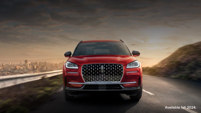 A 2025 red Lincoln Corsair® SUV is being driven down a road at sunset. | Oliver Lincoln in Plymouth IN