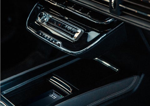 A smartphone is is being placed on the wireless charging pad in the front center console cubby. | Oliver Lincoln in Plymouth IN