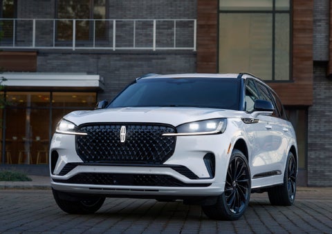 A 2026 Lincoln Aviator® Reserve model is shown with the available Jet Appearance Package parked near a restaurant. | Oliver Lincoln in Plymouth IN