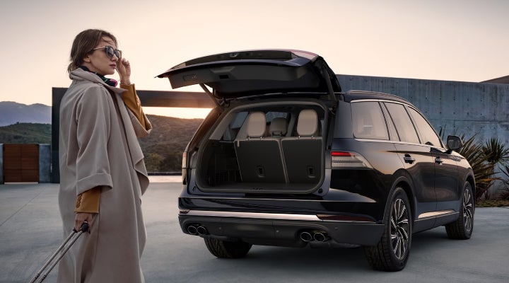 A woman approaches a 2026 Lincoln Aviator® SUV with its rear liftgate open. | Oliver Lincoln in Plymouth IN