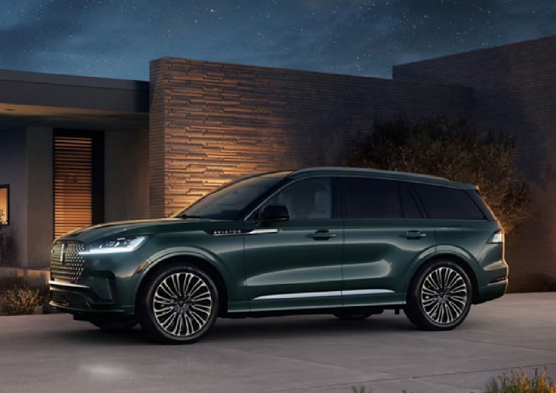 A green 2027 Lincoln Aviator® SUV is parked outside a contemporary home. | Oliver Lincoln in Plymouth IN