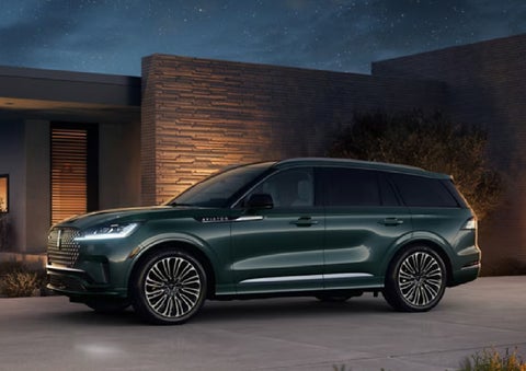 A green 2027 Lincoln Aviator® SUV is parked outside a contemporary home. | Oliver Lincoln in Plymouth IN