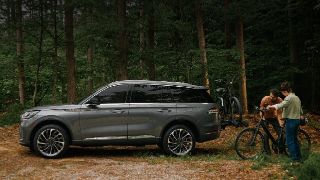 A father and son load e-bikes on a bike rack attached to a 2027 Lincoln Aviator® SUV. | Oliver Lincoln in Plymouth IN